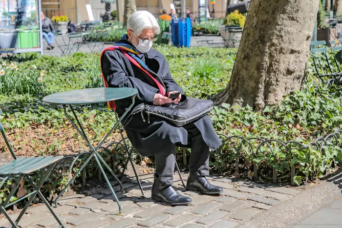 A photo of a man sitting in a park with a mask on